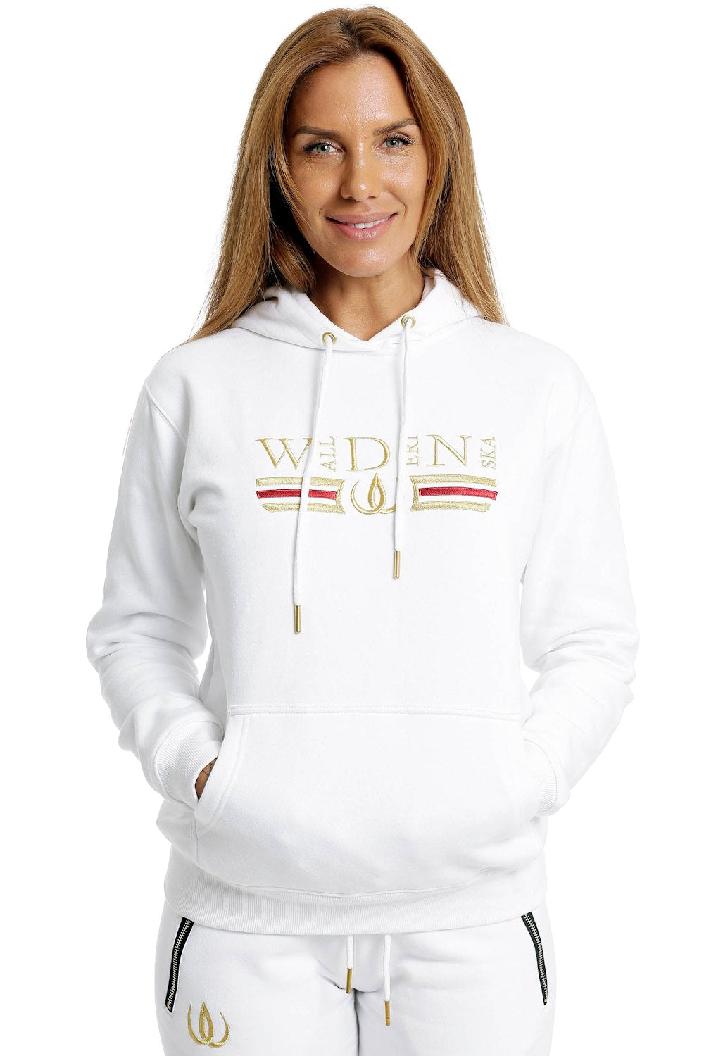 Deluxe Hoodie Vit med guldbroderi och rött streck över bröstet, buren till vita joggers.